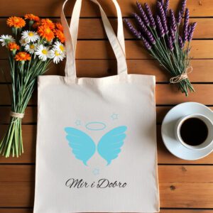 Bež platnena vrećica s tiskanim dizajnom leži na drvenoj podlozi. Na vrećici su plava anđeoska krila s aureolom iznad njih, okružena malim zvjezdicama. Ispod dizajna ispisan je tekst 'Mir i Dobro' elegantnim crnim rukopisnim fontom.